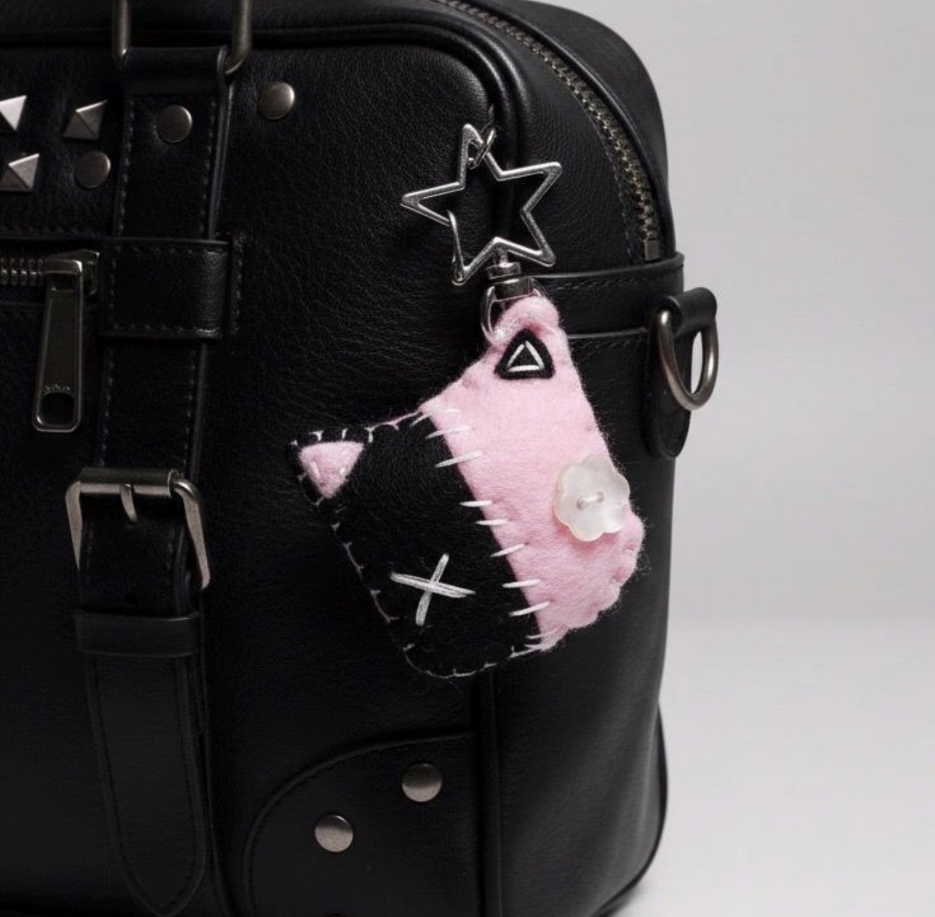 pink and black handmade felt cat keychain on a black bag